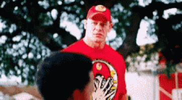 a man in a red shirt and hat is talking to another man .