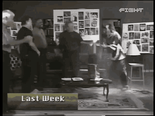 a group of people standing in a living room with a sign that says last week