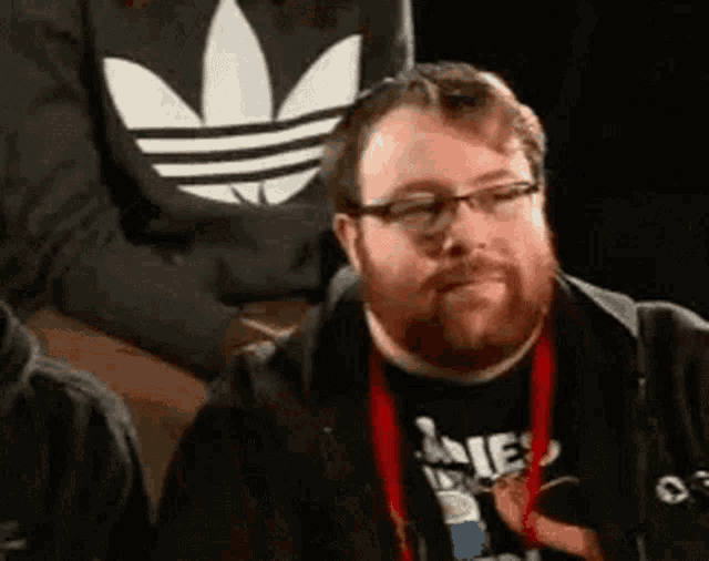 a man with a beard and glasses is wearing a black adidas shirt