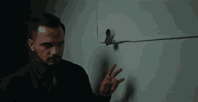 a man in a suit and tie is touching a wall .