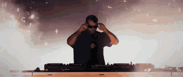 a man wearing sunglasses is playing music on a pioneer dj mixer