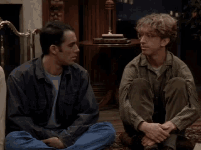 two men are sitting on the floor and one of them has the word zap on it
