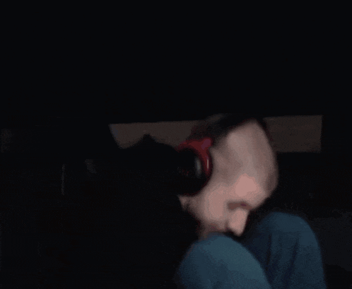 a man wearing headphones is sitting down in the dark