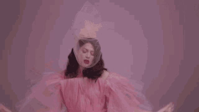 a woman in a pink dress is dancing with her arms outstretched .
