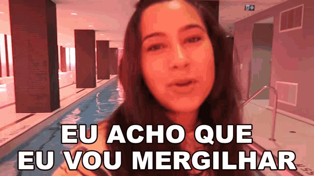 a woman stands in front of a swimming pool and says eu acho que eu vou mergilhar