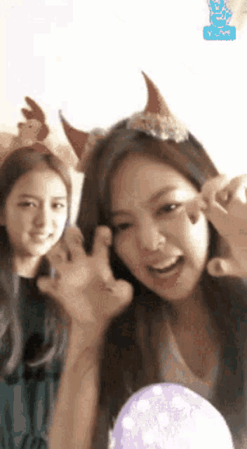a woman wearing a headband with a chicken on it stands next to another woman