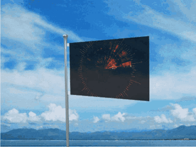 a flag with a picture of a clock on it is flying in the wind
