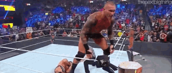 a man is wrestling another man in a wrestling ring with a crowd watching .
