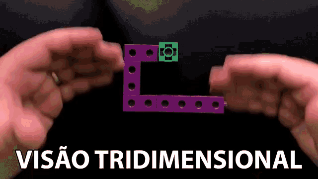 a person is holding a purple and green block with the words visao tridimensional written below it