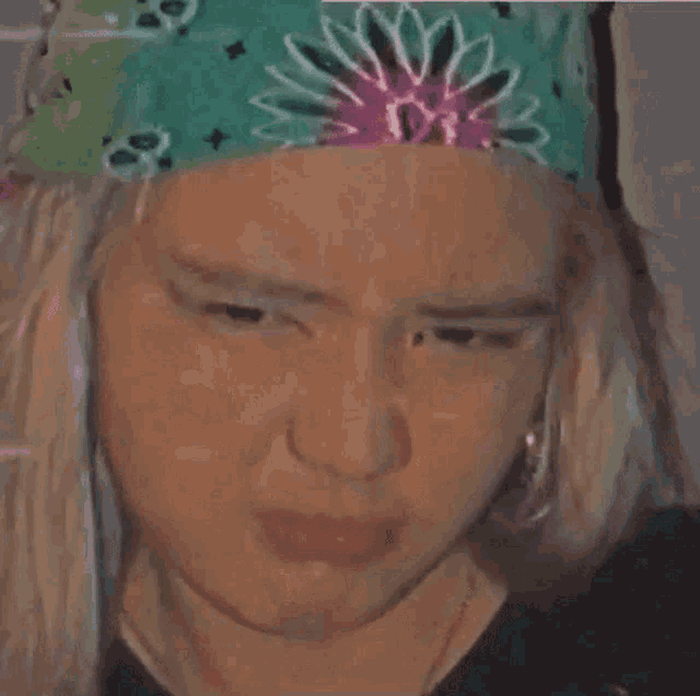 a close up of a woman wearing a green bandana with a flower on it .