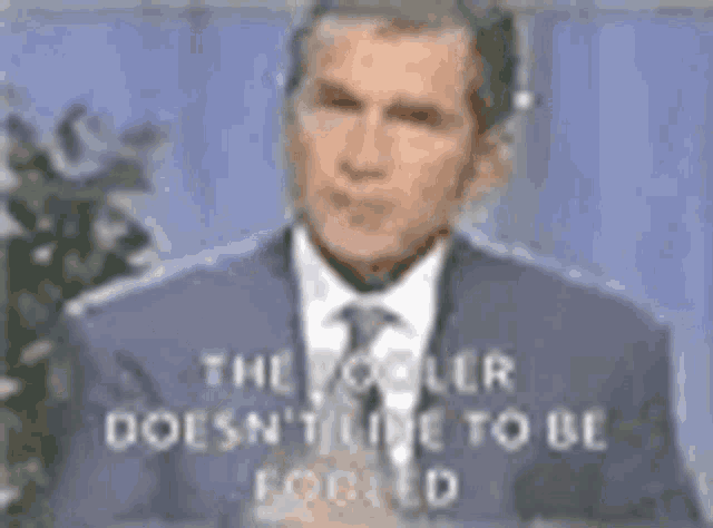 a man in a suit and tie is giving the middle finger to the camera .