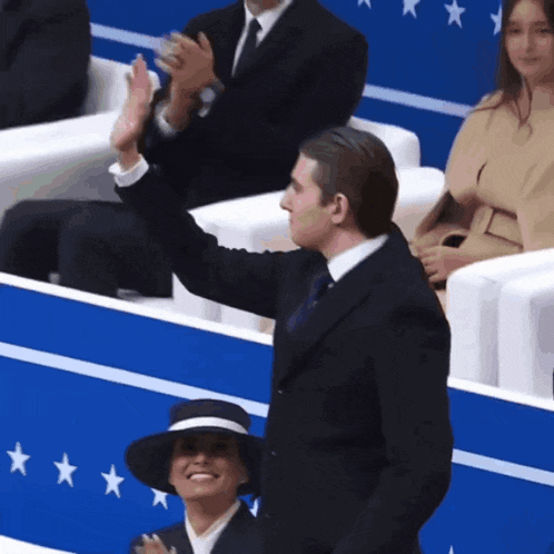 a man in a suit and tie is giving a high five