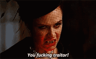a woman with a veil on her face is saying you fucking traitor .