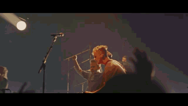 a man singing into a microphone while playing a guitar on stage
