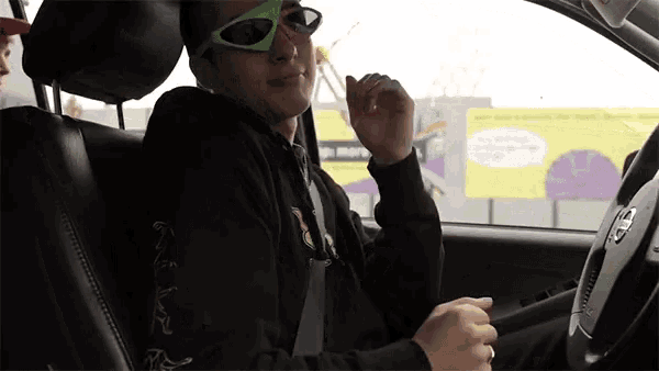 a man wearing sunglasses is sitting in the driver 's seat of a toyota car