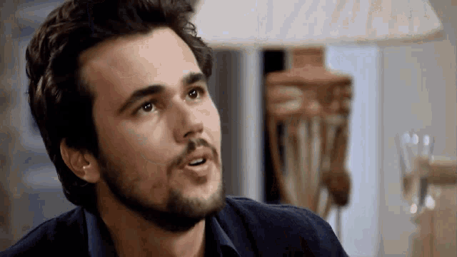 a man with a beard and ear piercings looks to the side