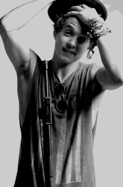 a black and white photo of a man wearing a hat and tank top