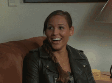 a woman in a leather jacket laughs with her mouth open