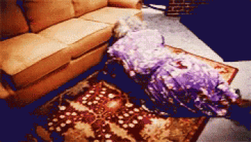 a woman in a purple dress is laying on a rug in front of a couch