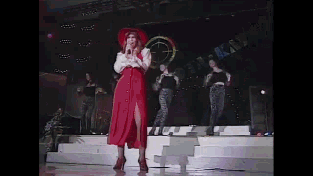 a woman in a red dress is singing on stage