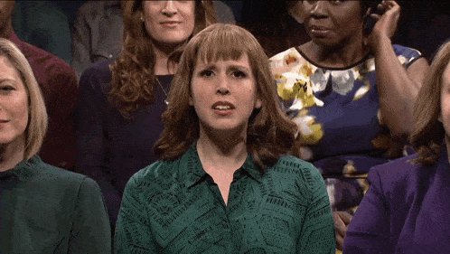 a woman in a green shirt is sitting in a crowd