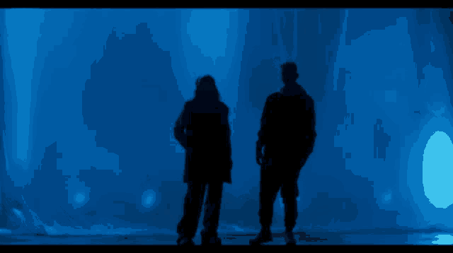 a couple of people standing in front of a blue light