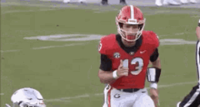 a football player with the number 13 on his jersey is running on the field .