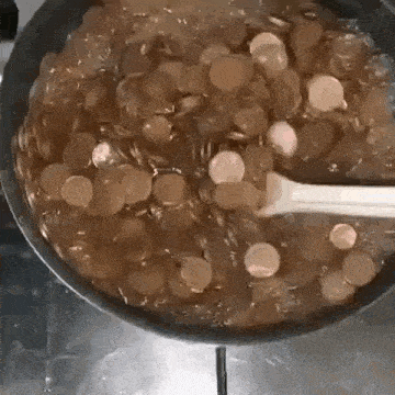 a pan filled with coins and a spoon in it on a stove .