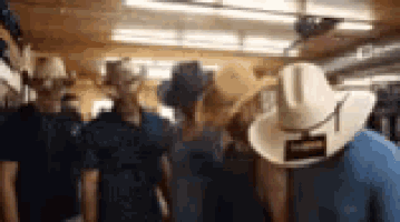 a group of people wearing cowboy hats are standing in a room .