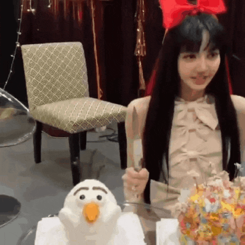 a woman is sitting at a table holding a knife next to a stuffed animal .