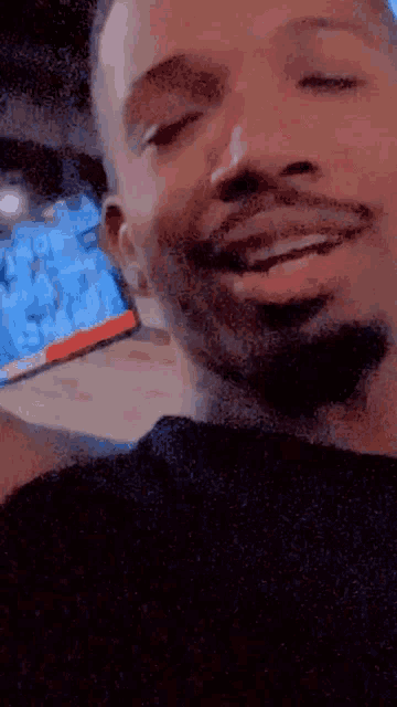 a man with a beard is smiling with his eyes closed and his mouth open