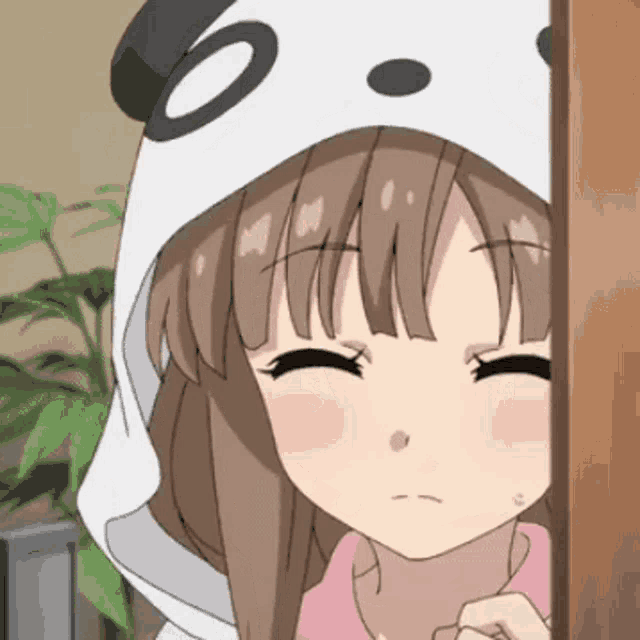 a girl wearing a panda hooded jacket is peeking out from behind a wall .