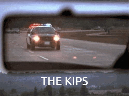 a police car is driving down a highway in a rear view mirror with the words the kips above it