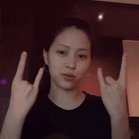 a woman in a black shirt is making a devil horns sign with her hands
