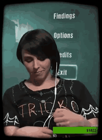 a woman wearing a trick or treat shirt is playing a video game .