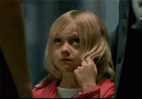 a little girl in a pink jacket is looking at her hair
