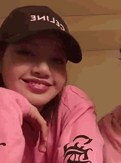 a close up of a woman wearing a hat and a pink hoodie .