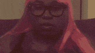 a woman with pink hair and glasses is making a face