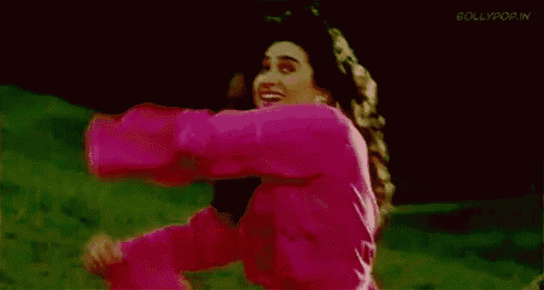 a woman in a pink shirt is dancing on a green field .