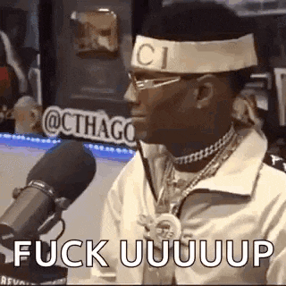 a man wearing a gucci headband is talking into a microphone .