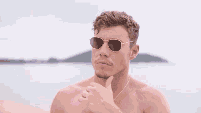 a man without a shirt is wearing sunglasses