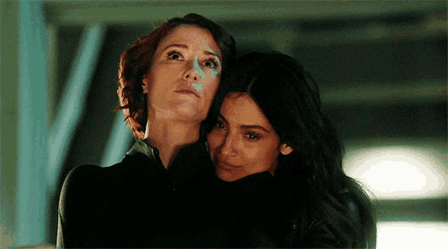 two women are hugging each other and looking up .