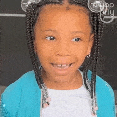 a little girl with braids and bubbles in her hair is wearing a blue jacket and smiling .