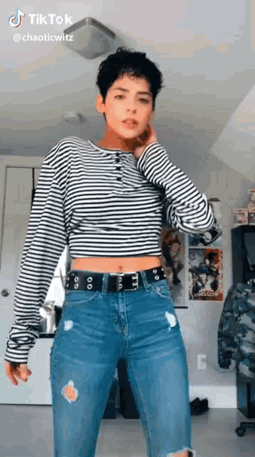 a woman is wearing a striped crop top and ripped jeans