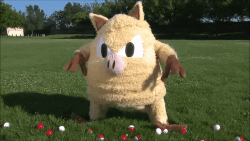 a stuffed animal is standing in the grass with golf balls