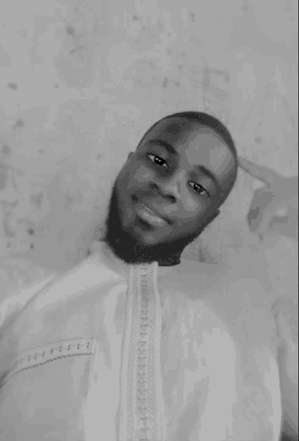 a black and white photo of a young man with a beard and a white shirt .