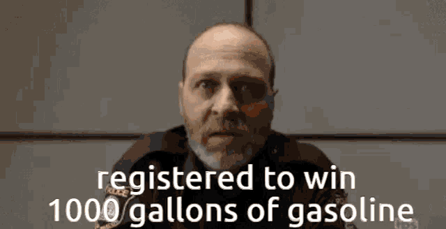 a man with a beard is sitting in front of a sign that says " registered to win 1000 gallons of gasoline "