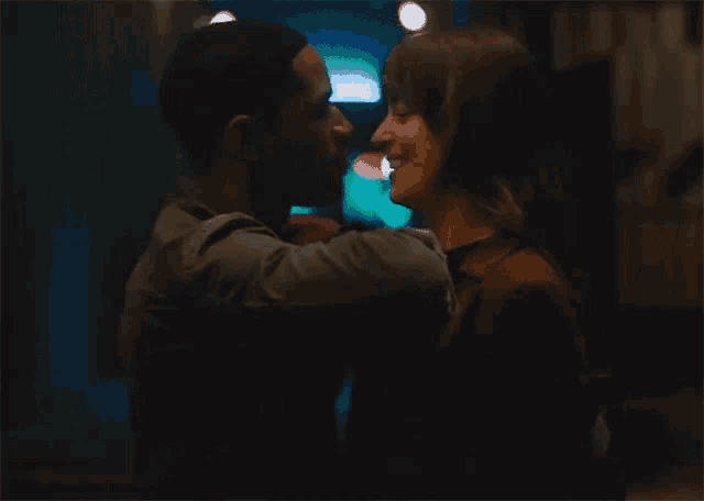 a man and woman are kissing in the dark .