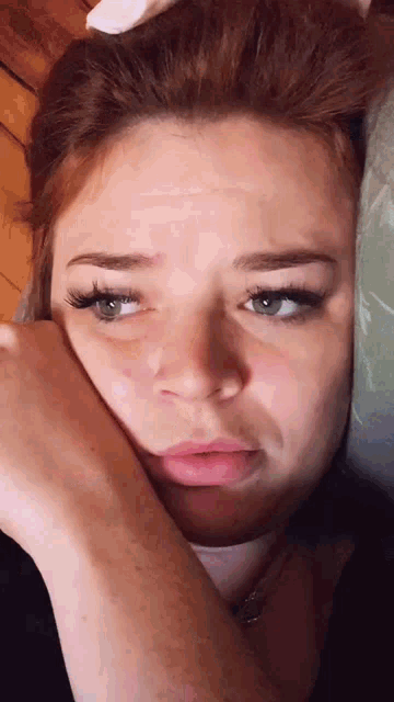 a close up of a woman 's face with a hand on her face .