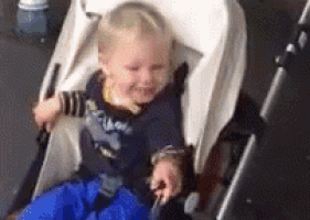 a baby is sitting in a stroller with a blue blanket on .